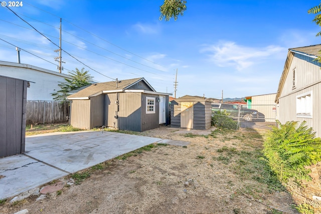 rear view of property with a storage unit and a patio area