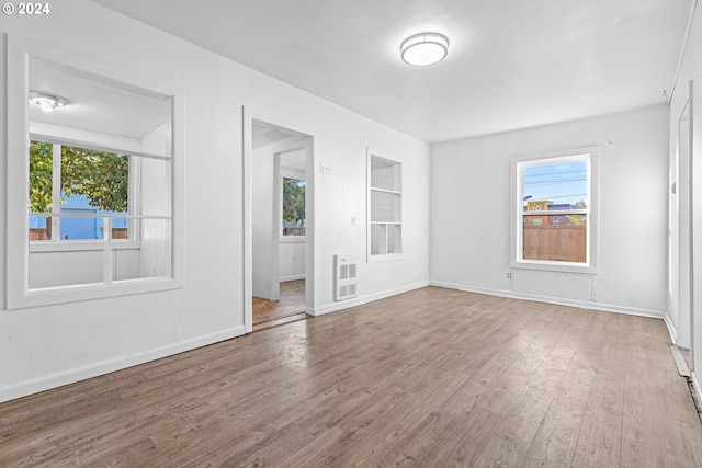 spare room featuring hardwood / wood-style floors, heating unit, and a healthy amount of sunlight