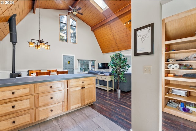 kitchen with a skylight, dark countertops, light brown cabinetry, wooden ceiling, and beamed ceiling