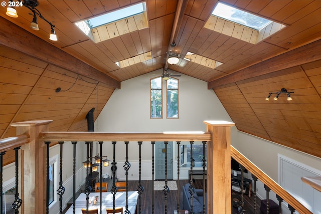 hall featuring wood ceiling, vaulted ceiling with skylight, wood finished floors, and an upstairs landing