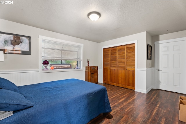 bedroom featuring a closet, dark wood-style flooring, wainscoting, and a textured ceiling