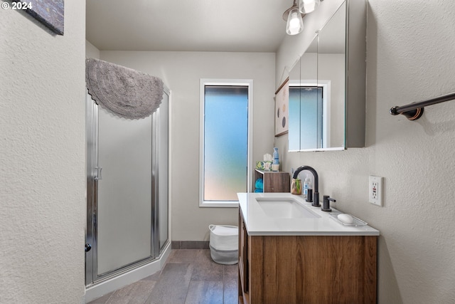 bathroom featuring vanity, baseboards, a shower stall, and a textured wall