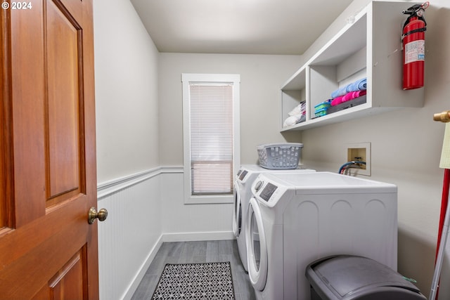 laundry area featuring laundry area, separate washer and dryer, a wainscoted wall, and wood finished floors