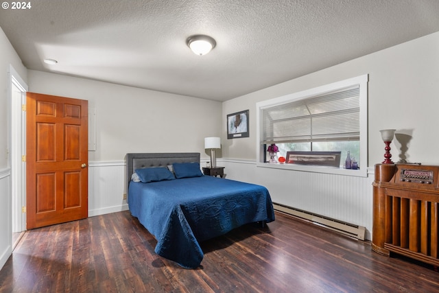 bedroom featuring a textured ceiling, a wainscoted wall, baseboard heating, and wood finished floors