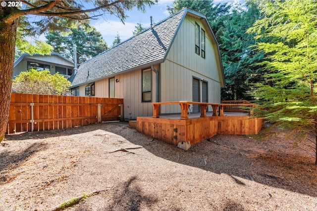 exterior space with roof with shingles, fence, and a gambrel roof