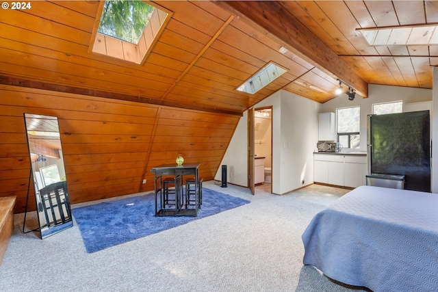 bedroom featuring carpet floors, lofted ceiling with skylight, freestanding refrigerator, and wooden walls