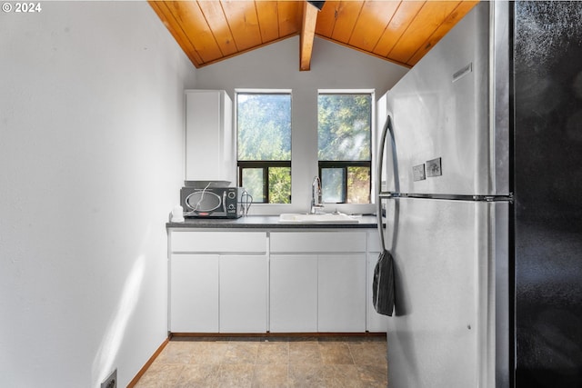 kitchen featuring a sink, freestanding refrigerator, dark countertops, vaulted ceiling with beams, and wooden ceiling