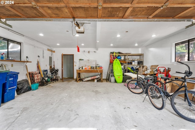 garage featuring a workshop area, recessed lighting, electric panel, and a garage door opener