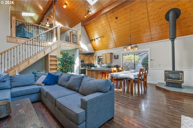 living area featuring high vaulted ceiling, dark wood-style flooring, a wood stove, wooden ceiling, and stairs