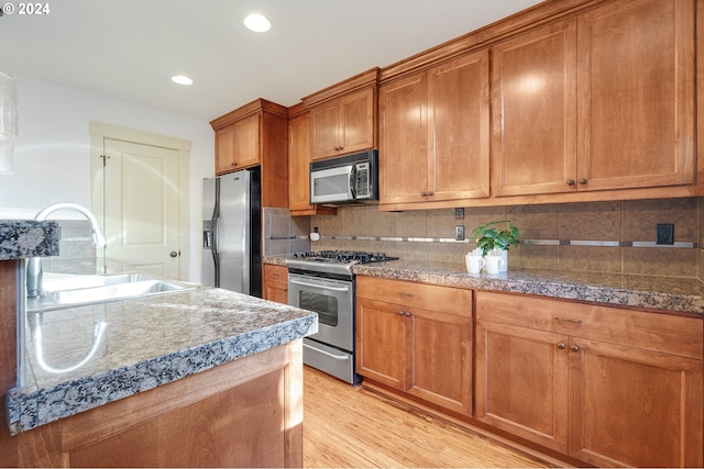 kitchen featuring decorative backsplash, appliances with stainless steel finishes, light hardwood / wood-style flooring, and sink