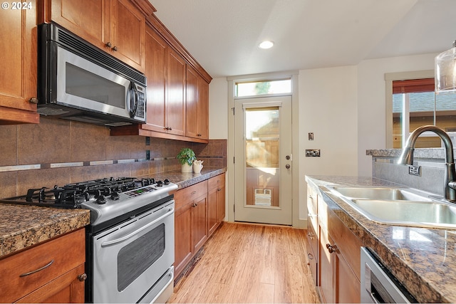 kitchen with stainless steel appliances, light hardwood / wood-style floors, decorative backsplash, and sink