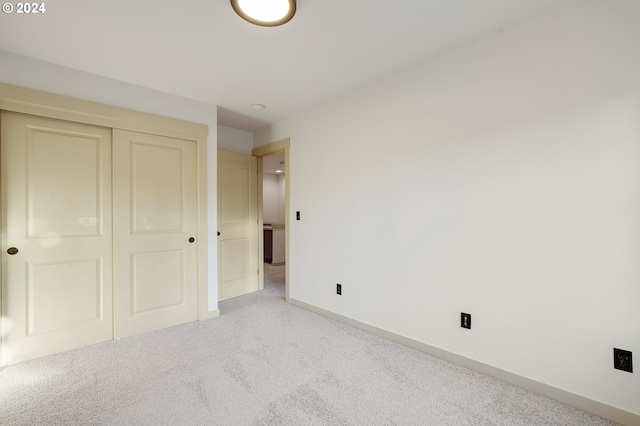 unfurnished bedroom with light carpet and a closet