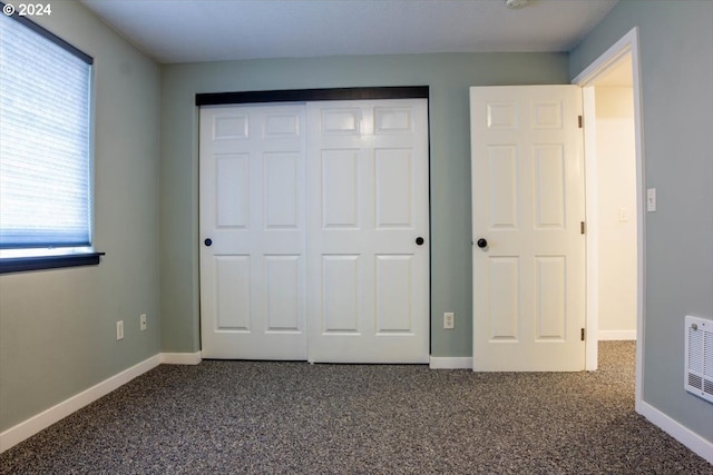 unfurnished bedroom featuring dark carpet and a closet