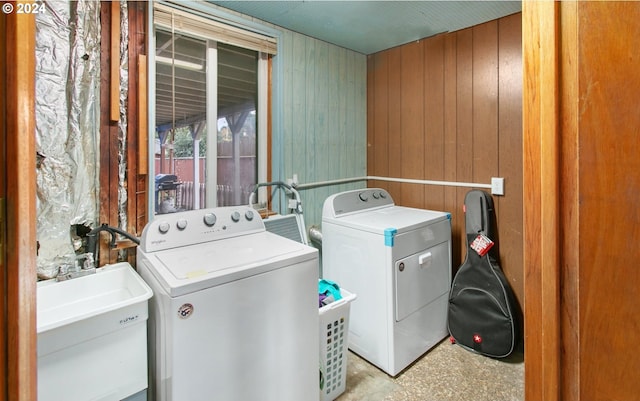 laundry room featuring washing machine and dryer, wood walls, and sink