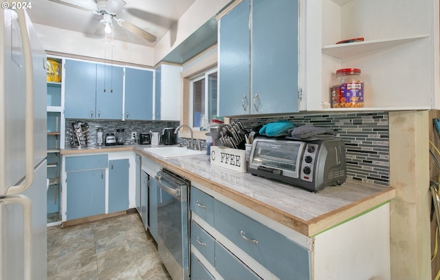 kitchen featuring tasteful backsplash, stainless steel dishwasher, blue cabinets, sink, and white fridge