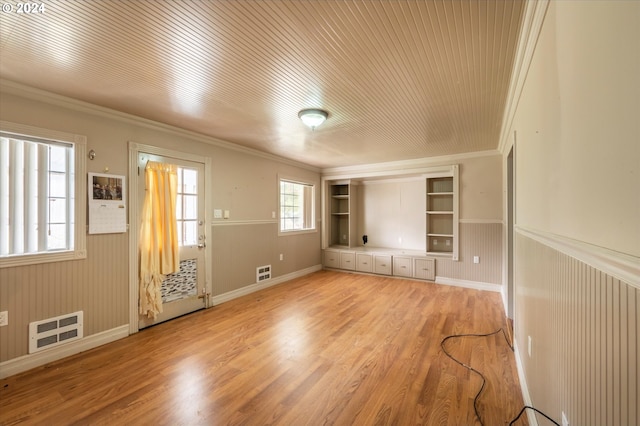 unfurnished living room featuring built in features, wood walls, hardwood / wood-style flooring, and ornamental molding