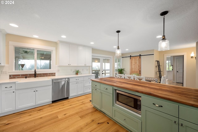 kitchen featuring pendant lighting, a wealth of natural light, a barn door, and appliances with stainless steel finishes