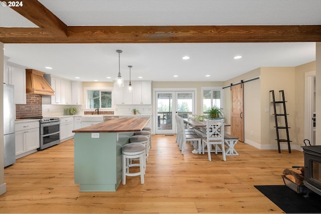 kitchen with premium range hood, a barn door, white cabinets, and appliances with stainless steel finishes