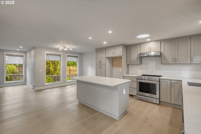 kitchen with stainless steel range, light hardwood / wood-style floors, a kitchen island, and gray cabinetry