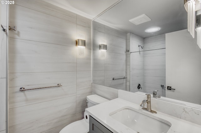 bathroom with vanity, a shower, tile walls, and toilet