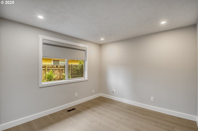 spare room featuring light hardwood / wood-style floors and a textured ceiling