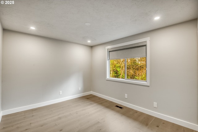 empty room featuring a textured ceiling and light wood-type flooring