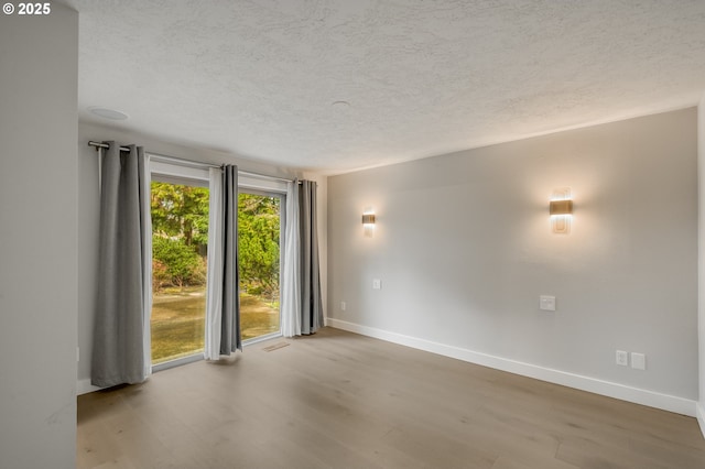 empty room with a textured ceiling and light hardwood / wood-style flooring