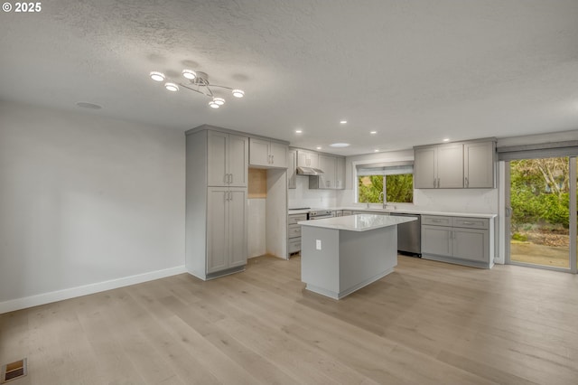 kitchen featuring dishwasher, a kitchen island, gray cabinetry, and light hardwood / wood-style flooring