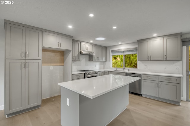 kitchen featuring gray cabinets, a kitchen island, appliances with stainless steel finishes, sink, and light hardwood / wood-style floors