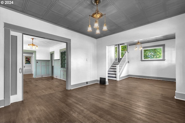 spare room with dark hardwood / wood-style floors and an inviting chandelier