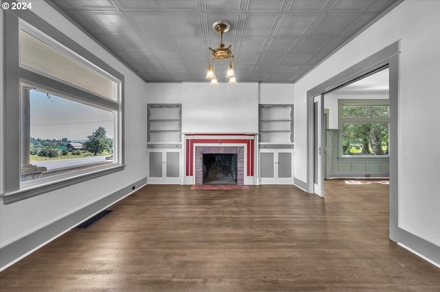 unfurnished living room with built in shelves, dark hardwood / wood-style flooring, a fireplace, and a wealth of natural light