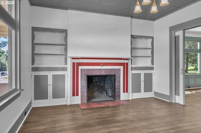 unfurnished living room with built in shelves, a fireplace, dark hardwood / wood-style floors, and a notable chandelier