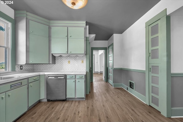 kitchen featuring sink, tasteful backsplash, stainless steel dishwasher, light wood-type flooring, and green cabinetry