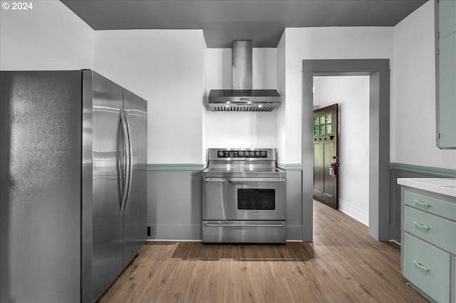 kitchen with stainless steel appliances, wall chimney range hood, and light wood-type flooring