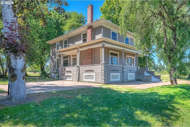 rear view of house featuring a yard and a porch