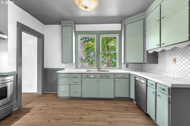 kitchen featuring dishwasher, sink, decorative backsplash, light hardwood / wood-style floors, and range