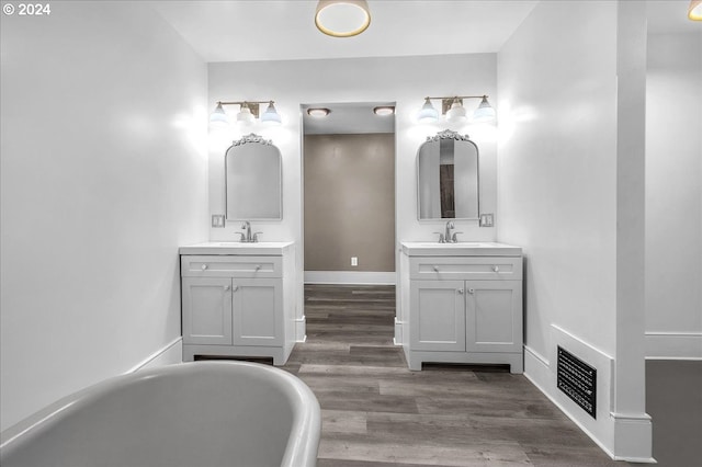 bathroom with a tub to relax in, vanity, and wood-type flooring