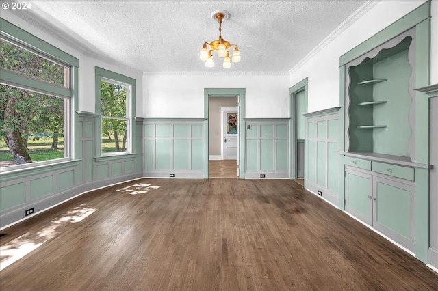 unfurnished dining area featuring crown molding, dark wood-type flooring, a textured ceiling, and a notable chandelier