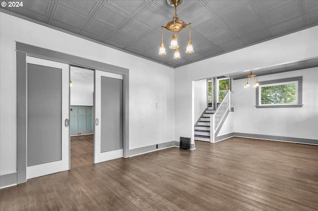 spare room with dark hardwood / wood-style floors and a notable chandelier