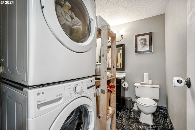 laundry room featuring a textured ceiling and stacked washing maching and dryer