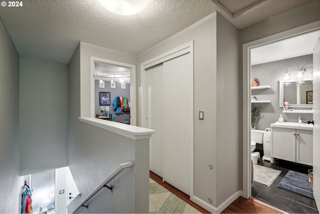 corridor featuring a textured ceiling, sink, and dark hardwood / wood-style flooring