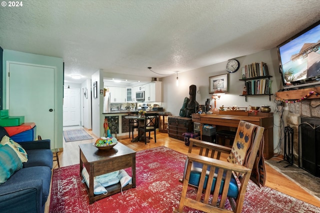 living room with light hardwood / wood-style floors, a fireplace, and a textured ceiling