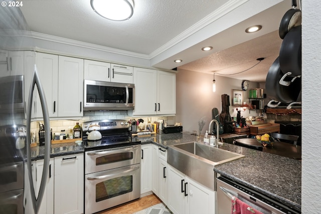 kitchen featuring white cabinets, a textured ceiling, appliances with stainless steel finishes, and ornamental molding