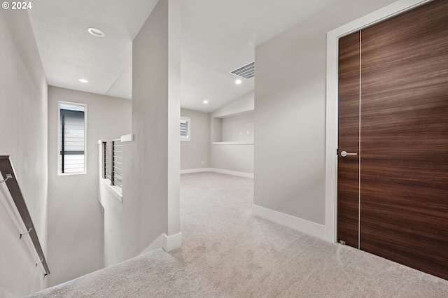 hall with vaulted ceiling and light colored carpet