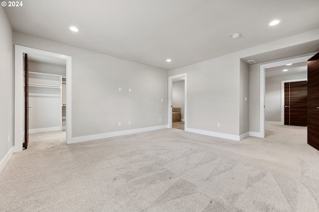 unfurnished bedroom with light carpet, a closet, and a walk in closet