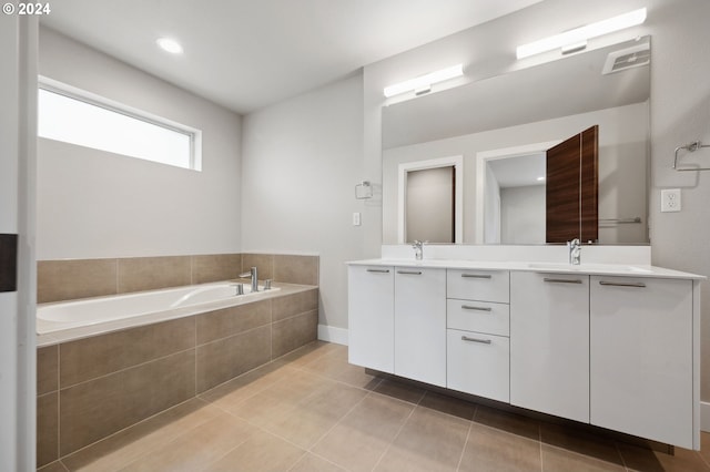 bathroom with tiled tub, tile patterned flooring, and vanity