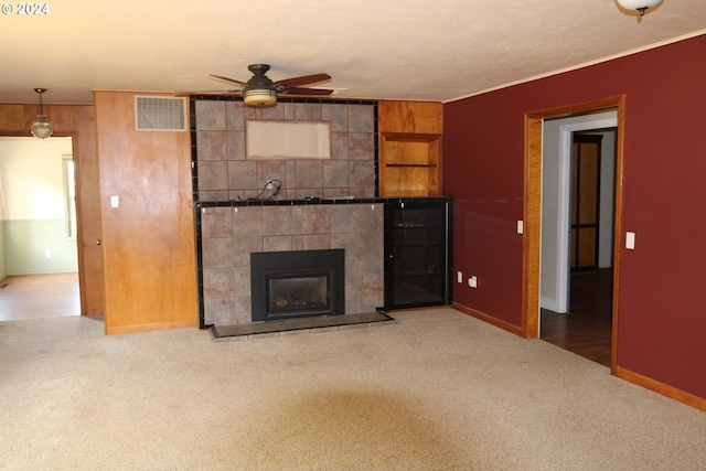 unfurnished living room with ceiling fan, carpet floors, and a fireplace