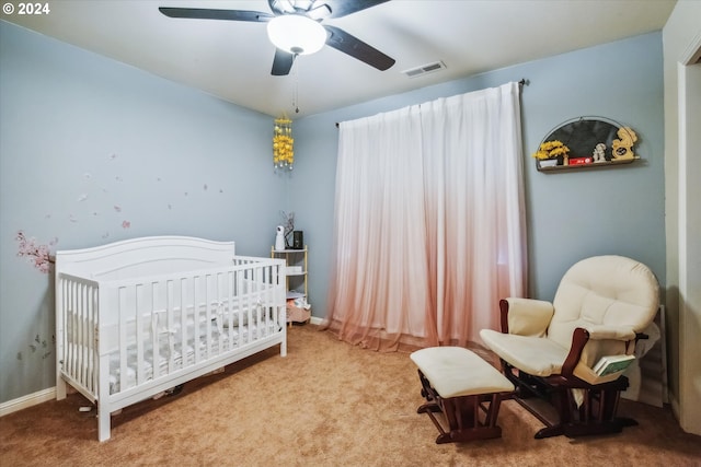 bedroom with a nursery area, carpet flooring, and ceiling fan