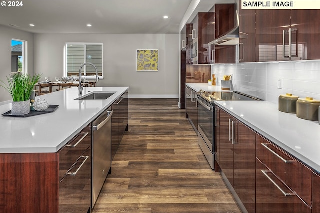 kitchen with stainless steel appliances, a center island with sink, sink, tasteful backsplash, and dark hardwood / wood-style floors