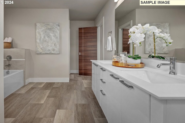 bathroom featuring hardwood / wood-style flooring, vanity, and a washtub